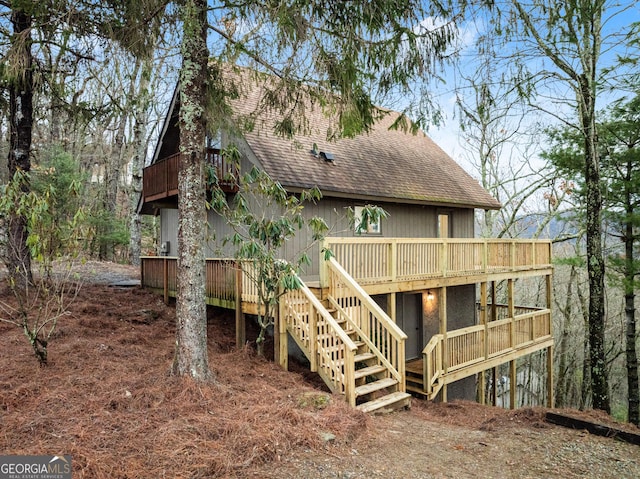 back of house featuring a shingled roof, stairway, and a deck