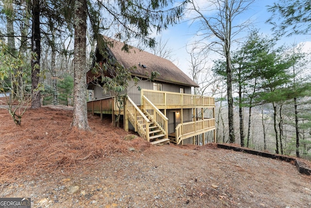 back of property with roof with shingles, a deck, and stairs