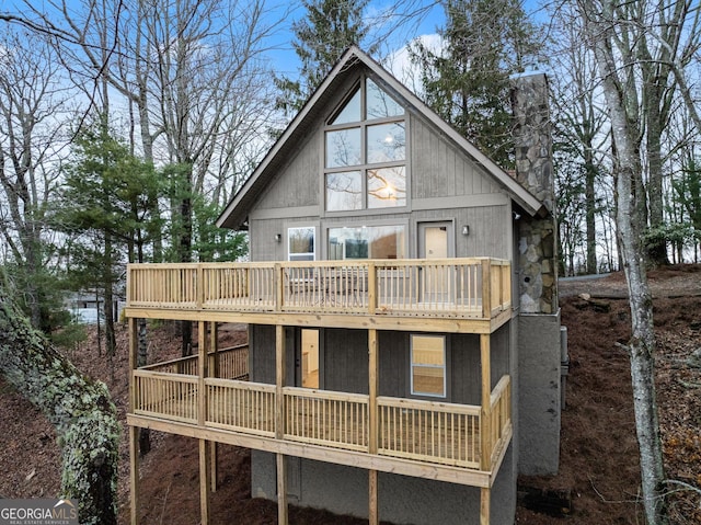 rear view of house with a chimney and a wooden deck