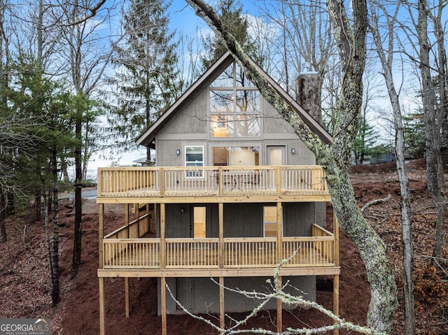 back of house with a chimney and a deck