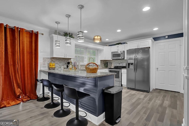 kitchen with appliances with stainless steel finishes, kitchen peninsula, hanging light fixtures, and white cabinets