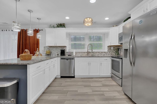 kitchen featuring pendant lighting, sink, appliances with stainless steel finishes, white cabinetry, and kitchen peninsula