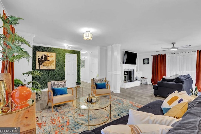 living room with hardwood / wood-style flooring, ceiling fan, a fireplace, and crown molding