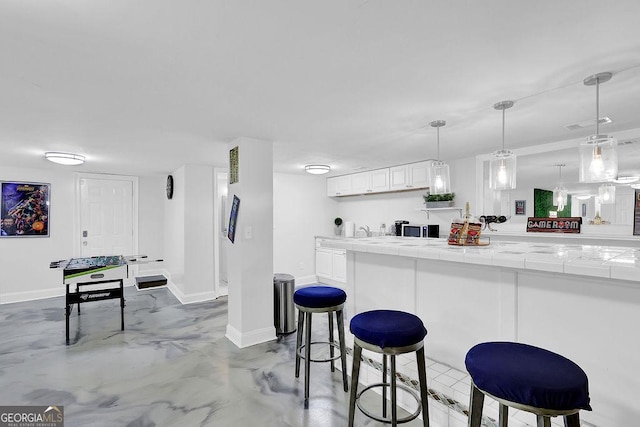 kitchen featuring hanging light fixtures, tile counters, white cabinets, and kitchen peninsula