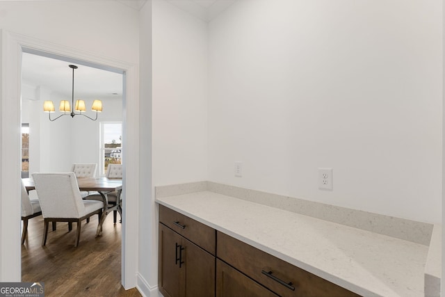 interior space featuring pendant lighting, a chandelier, dark hardwood / wood-style flooring, dark brown cabinetry, and light stone countertops