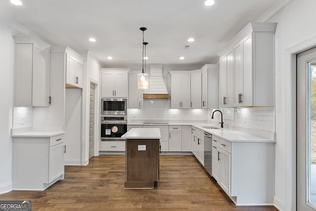 kitchen featuring sink, appliances with stainless steel finishes, a kitchen island, custom range hood, and white cabinets