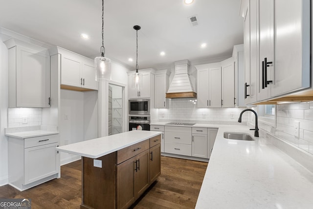 kitchen with sink, premium range hood, stainless steel appliances, a center island, and white cabinets