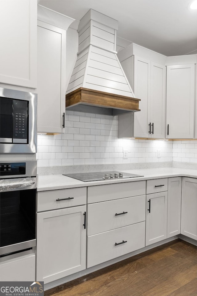 kitchen featuring backsplash, appliances with stainless steel finishes, custom range hood, and white cabinets