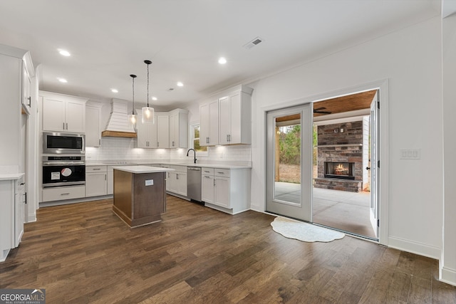 kitchen with a kitchen island, white cabinetry, appliances with stainless steel finishes, and pendant lighting