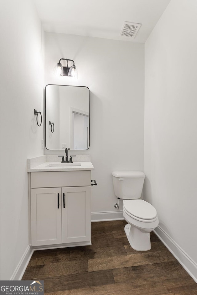 bathroom featuring wood-type flooring, vanity, and toilet