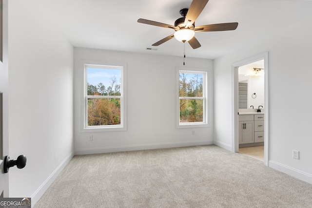 unfurnished bedroom with connected bathroom, light colored carpet, and ceiling fan