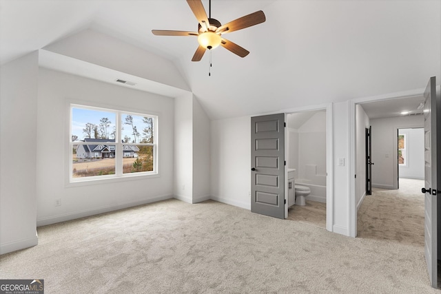 unfurnished bedroom featuring vaulted ceiling, light colored carpet, ceiling fan, and ensuite bathroom