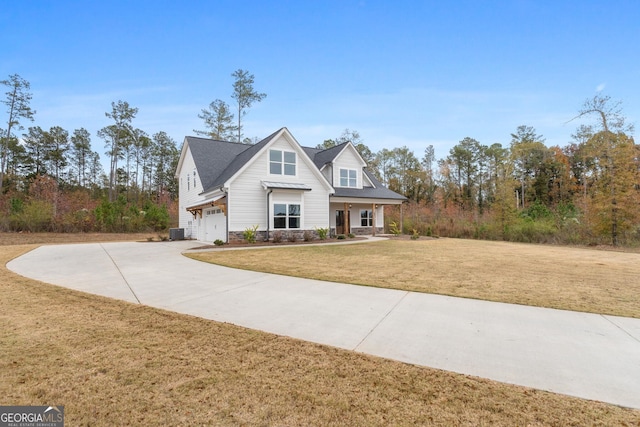 view of front of property featuring a garage, central AC, and a front yard