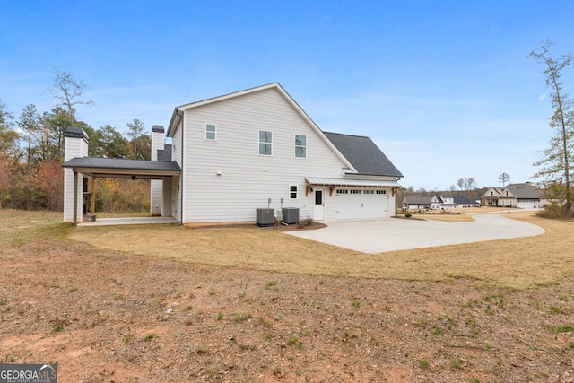 back of property featuring a garage, a yard, and cooling unit