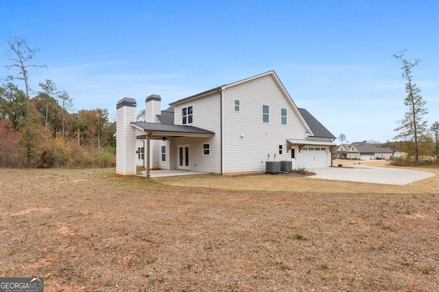 rear view of property with a garage, a yard, a patio area, and central air condition unit