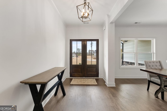 foyer with crown molding, dark hardwood / wood-style floors, and french doors