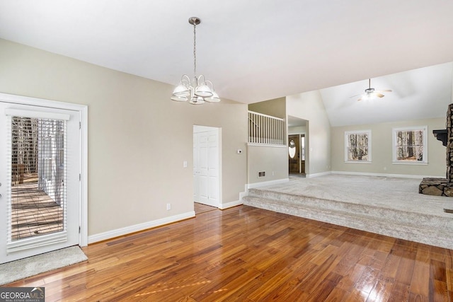 unfurnished living room featuring vaulted ceiling, plenty of natural light, ceiling fan with notable chandelier, and hardwood / wood-style floors