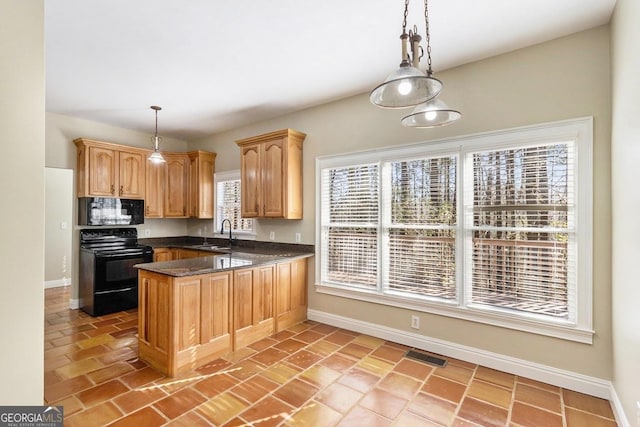 kitchen featuring sink, kitchen peninsula, pendant lighting, dark stone counters, and black appliances