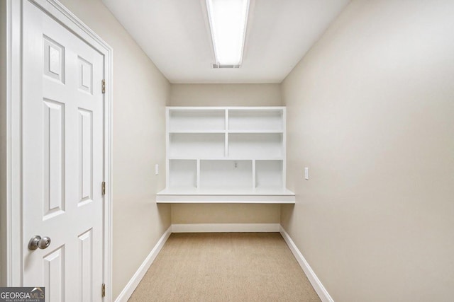 interior space featuring built in desk and light colored carpet