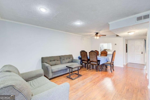 living room with crown molding, a textured ceiling, and light wood-type flooring