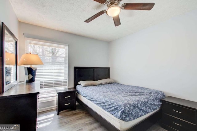 bedroom featuring ceiling fan, hardwood / wood-style floors, and a textured ceiling