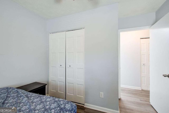 bedroom with wood-type flooring, a textured ceiling, and a closet