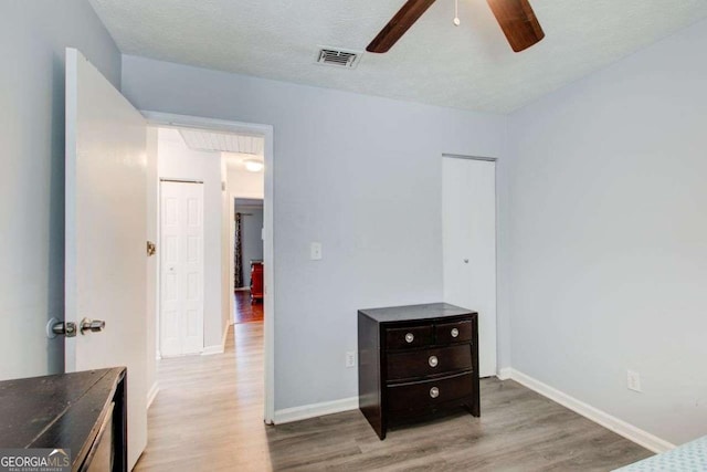 bedroom featuring ceiling fan, a textured ceiling, and light wood-type flooring