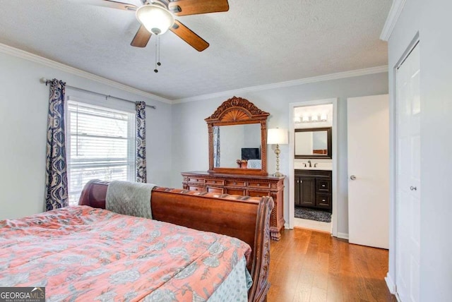 bedroom with ornamental molding, sink, light hardwood / wood-style floors, and a textured ceiling