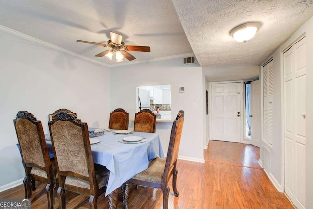 dining area with crown molding, ceiling fan, a textured ceiling, and light wood-type flooring