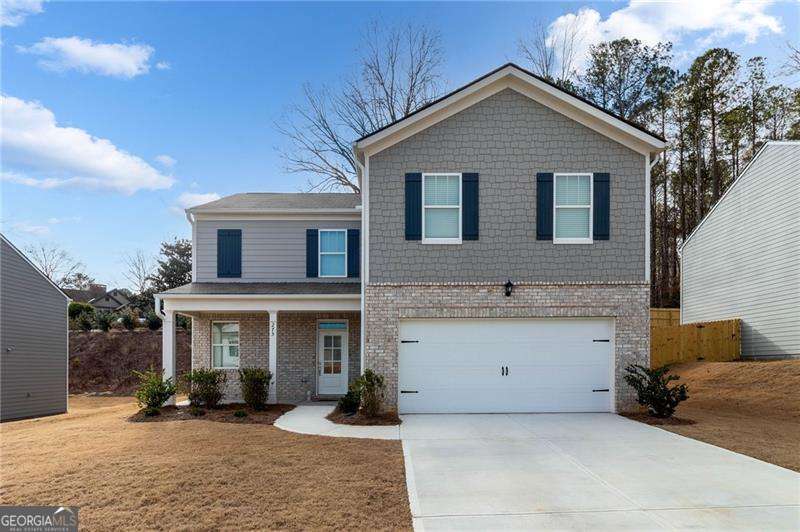 traditional-style home with a garage, concrete driveway, covered porch, a front lawn, and brick siding