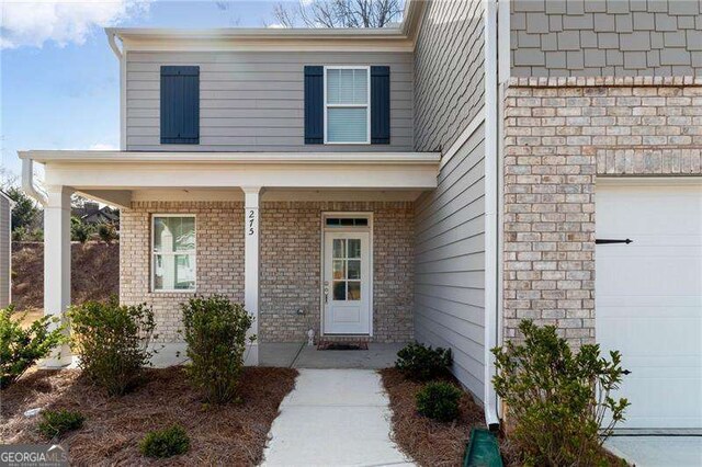 doorway to property featuring a porch and a garage