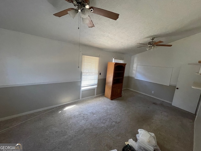 interior space featuring dark colored carpet, vaulted ceiling, ceiling fan, and a textured ceiling