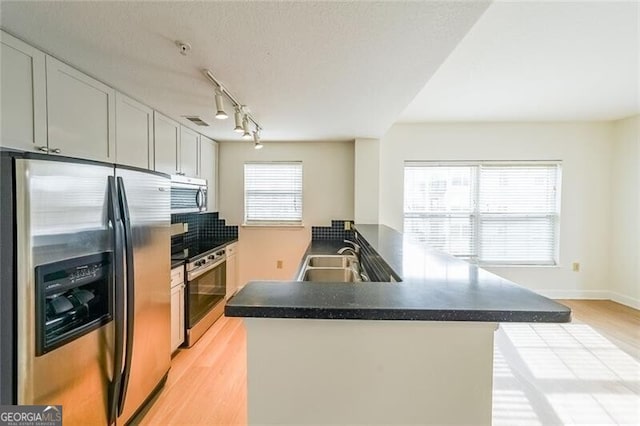 kitchen with stainless steel appliances, light hardwood / wood-style floors, sink, and kitchen peninsula