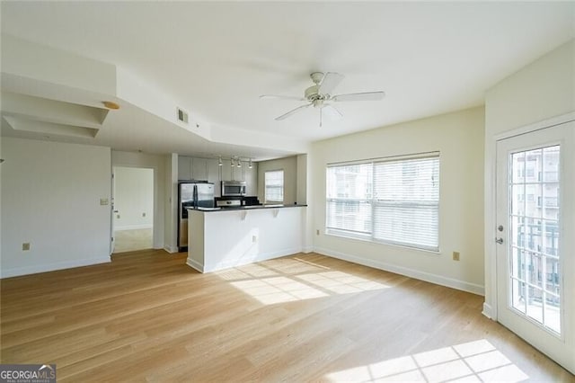 kitchen with ceiling fan, stainless steel appliances, kitchen peninsula, and light hardwood / wood-style flooring