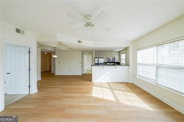 unfurnished living room featuring ceiling fan and light wood-type flooring