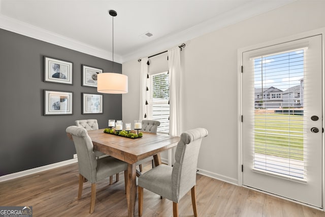 dining area with crown molding and light hardwood / wood-style floors