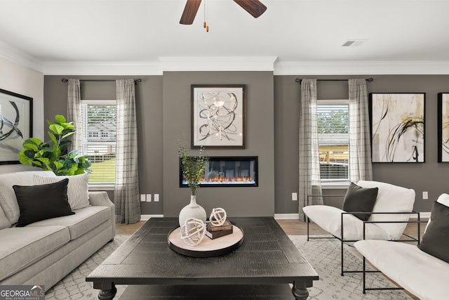 living room with crown molding, ceiling fan, a healthy amount of sunlight, and light hardwood / wood-style flooring