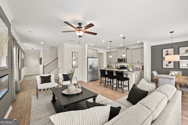 living room featuring ornamental molding, light hardwood / wood-style floors, and ceiling fan