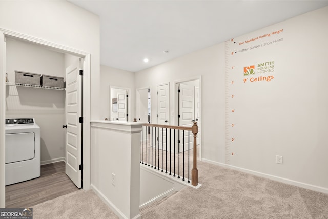 corridor with washer / clothes dryer and light colored carpet