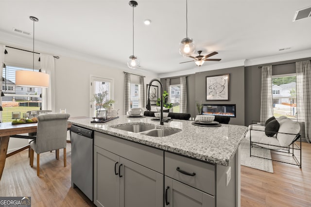 kitchen with sink, dishwasher, gray cabinetry, hanging light fixtures, and a center island with sink