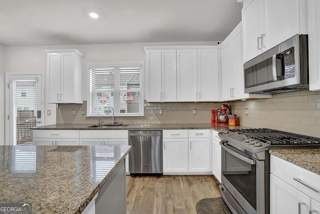 kitchen featuring stainless steel appliances, sink, dark stone countertops, and white cabinets