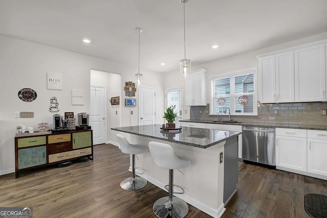 kitchen featuring stainless steel dishwasher, decorative light fixtures, a kitchen island, and white cabinets