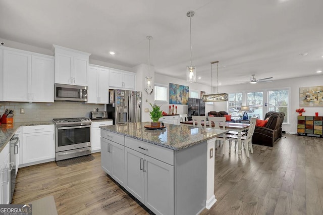 kitchen with light stone counters, stainless steel appliances, white cabinets, and a kitchen island