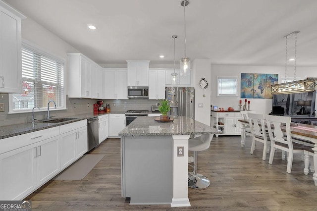 kitchen featuring sink, decorative light fixtures, a center island, appliances with stainless steel finishes, and white cabinets