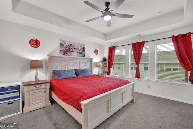 bedroom featuring light carpet, ceiling fan, and a tray ceiling