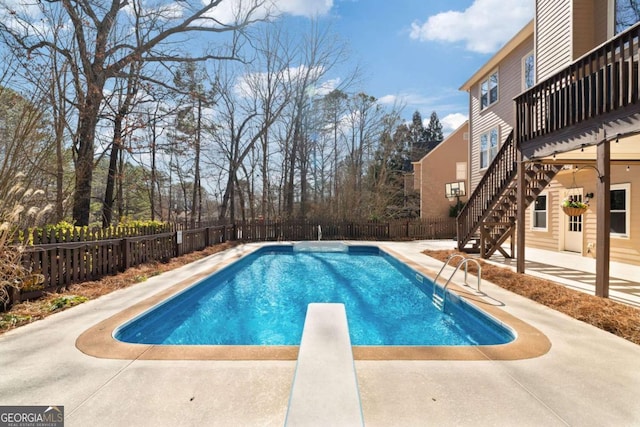 view of swimming pool with a diving board and a patio