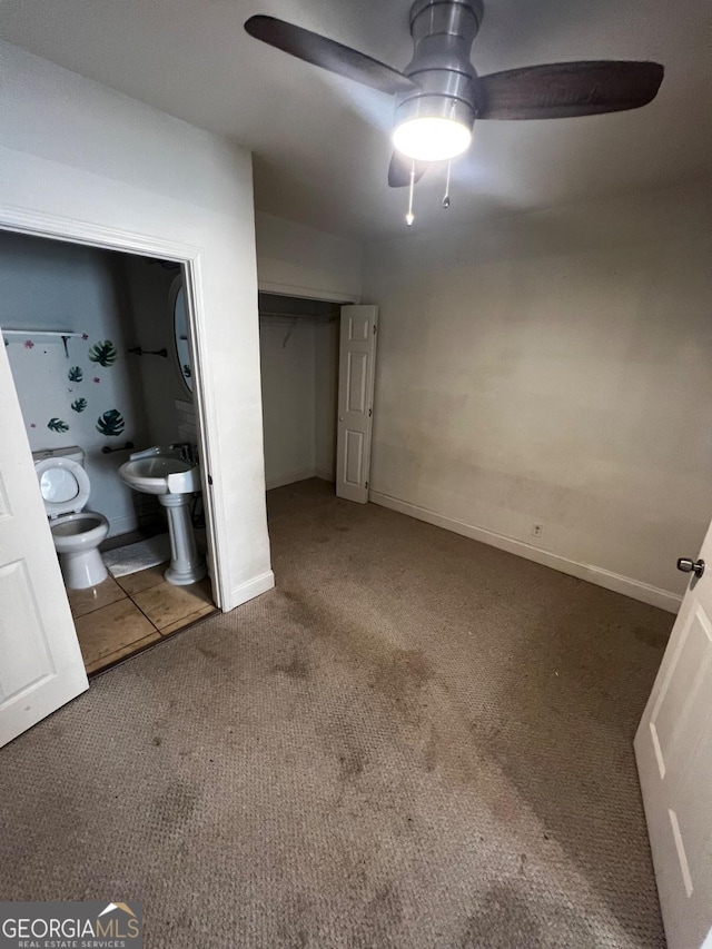 unfurnished bedroom with ceiling fan, ensuite bath, and carpet floors