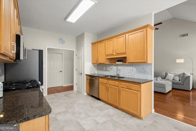 kitchen with sink, dark stone countertops, stove, vaulted ceiling, and stainless steel dishwasher