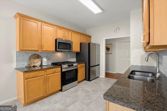 kitchen with dark stone countertops, sink, tasteful backsplash, and stainless steel appliances