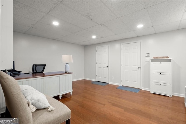 office with wood-type flooring and a drop ceiling